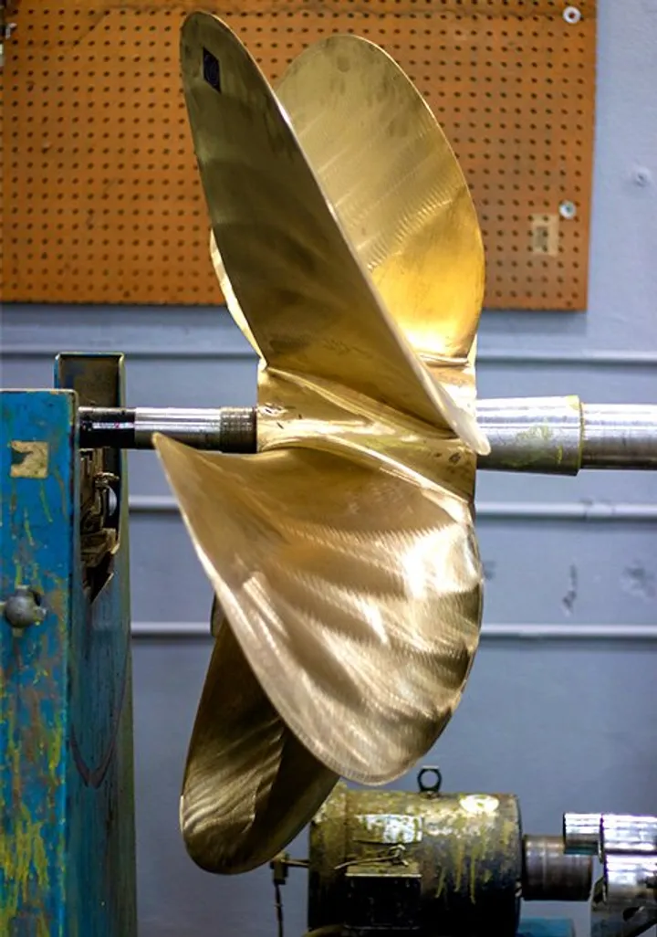 Reconditioned bronze propeller mounted on a shaft in the shop